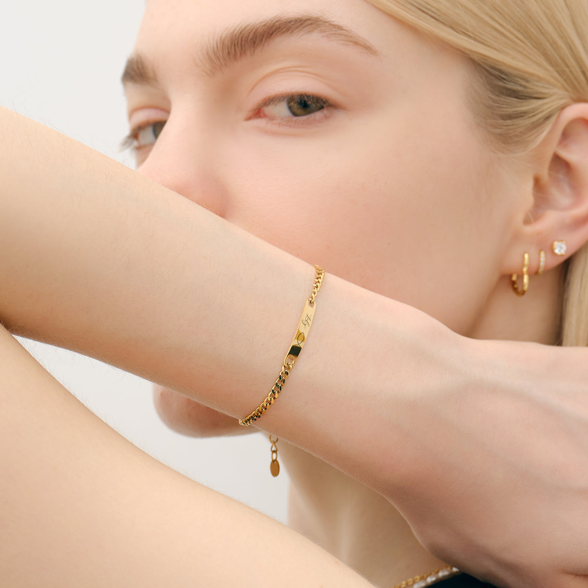 Frau trägt personalisiertes Unisex Armband in Gold mit graviertem Plättchen am Arm