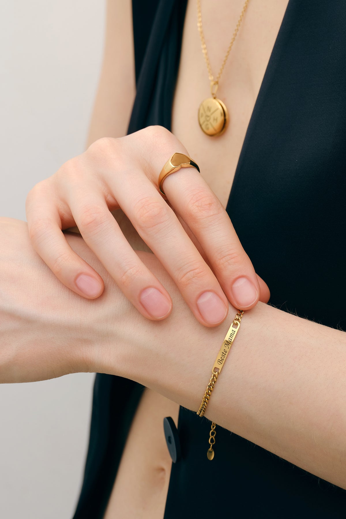 Frau trägt personalisiertes Unisex Armband in Gold mit Gravur Beste Mama zu Medaillon-Kette