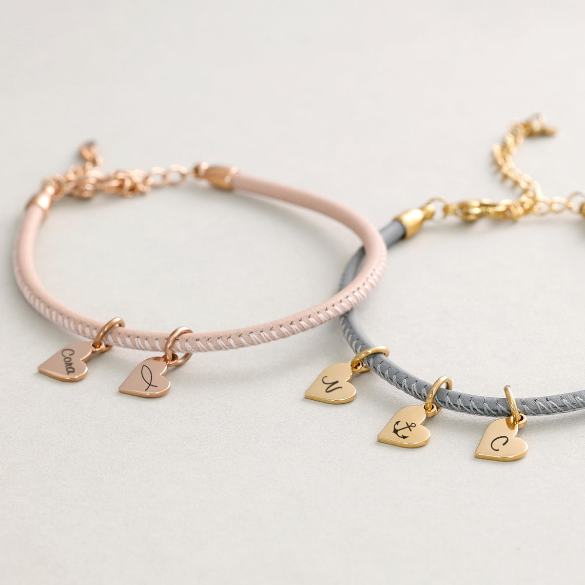 Lederarmband mit Gravur in Rosé und Grau nebeneinander, Herzanhänger mit Namen und Symbolen