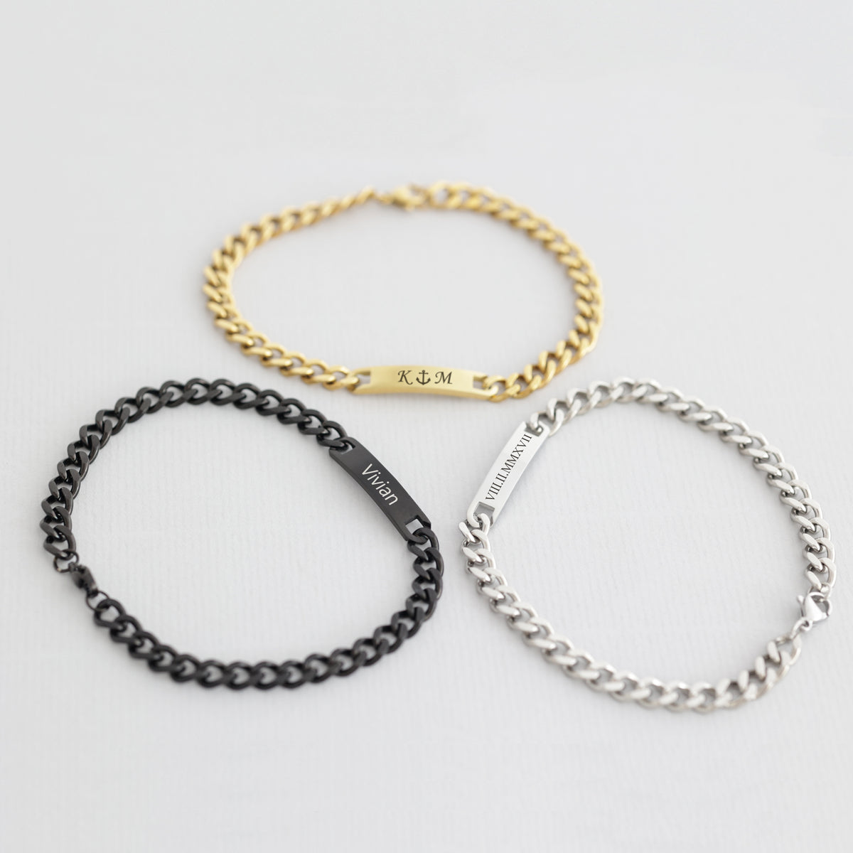Drei Panzerarmbänder in Gold, Schwarz und Silber mit gravierten Namensschildern