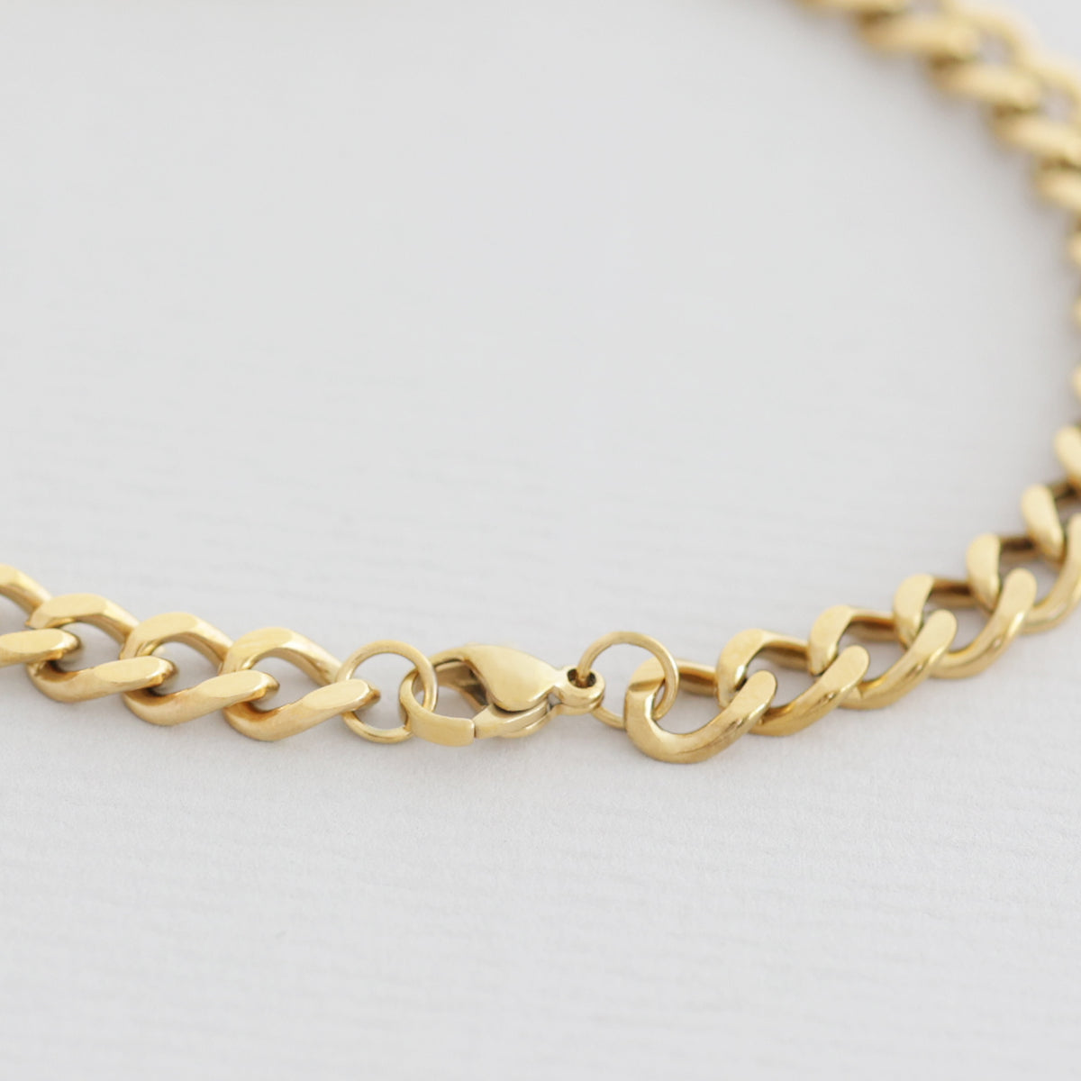 Nahaufnahme eines goldenen Panzerarmbands mit Karabinerverschluss