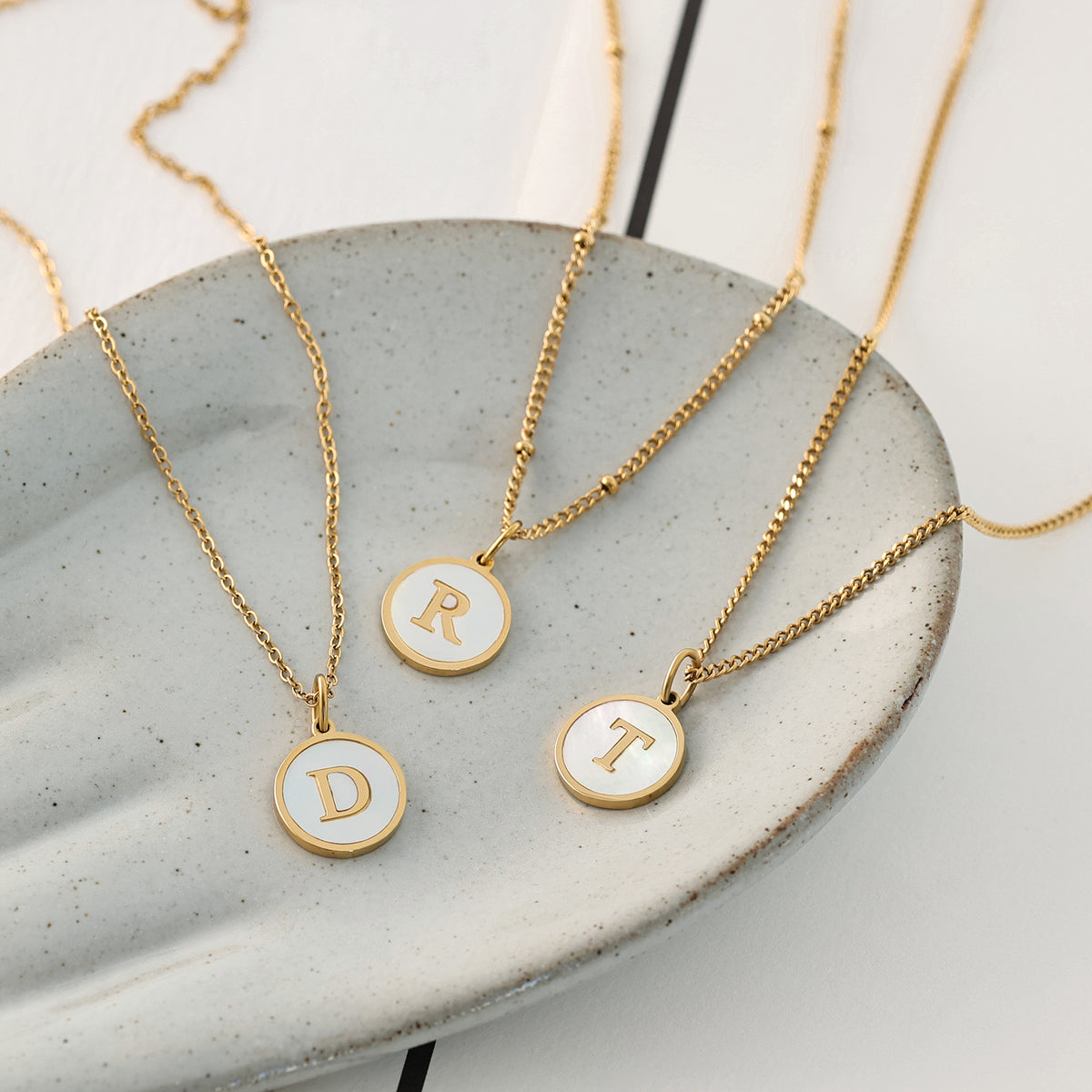 Initialenkette mit Perlmutt & Gravur – drei Ketten mit Buchstaben D, R und T in Gold nebeneinander