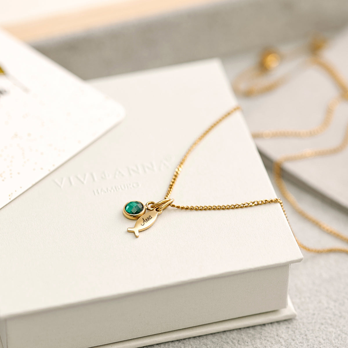 Ichthys Kette mit Geburtsstein – goldener Fisch-Anhänger graviert 'Anna' mit grünem Geburtsstein auf Geschenkbox