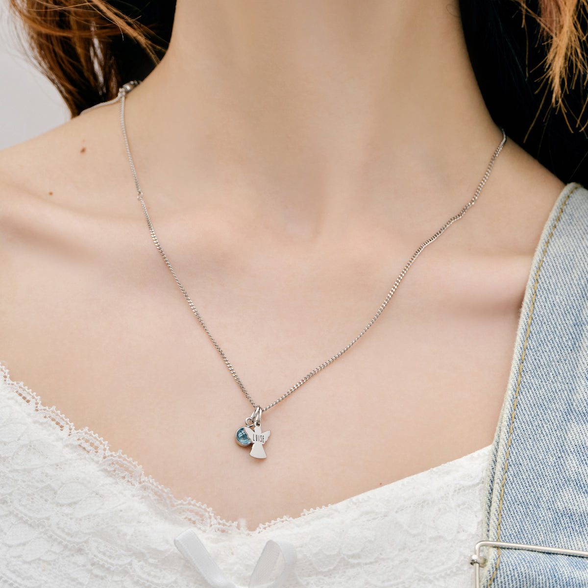 Schutzengel Kette mit Geburtsstein – Nahaufnahme Mädchen trägt silberne Engelkette mit Stein, Jeans-Latzhose