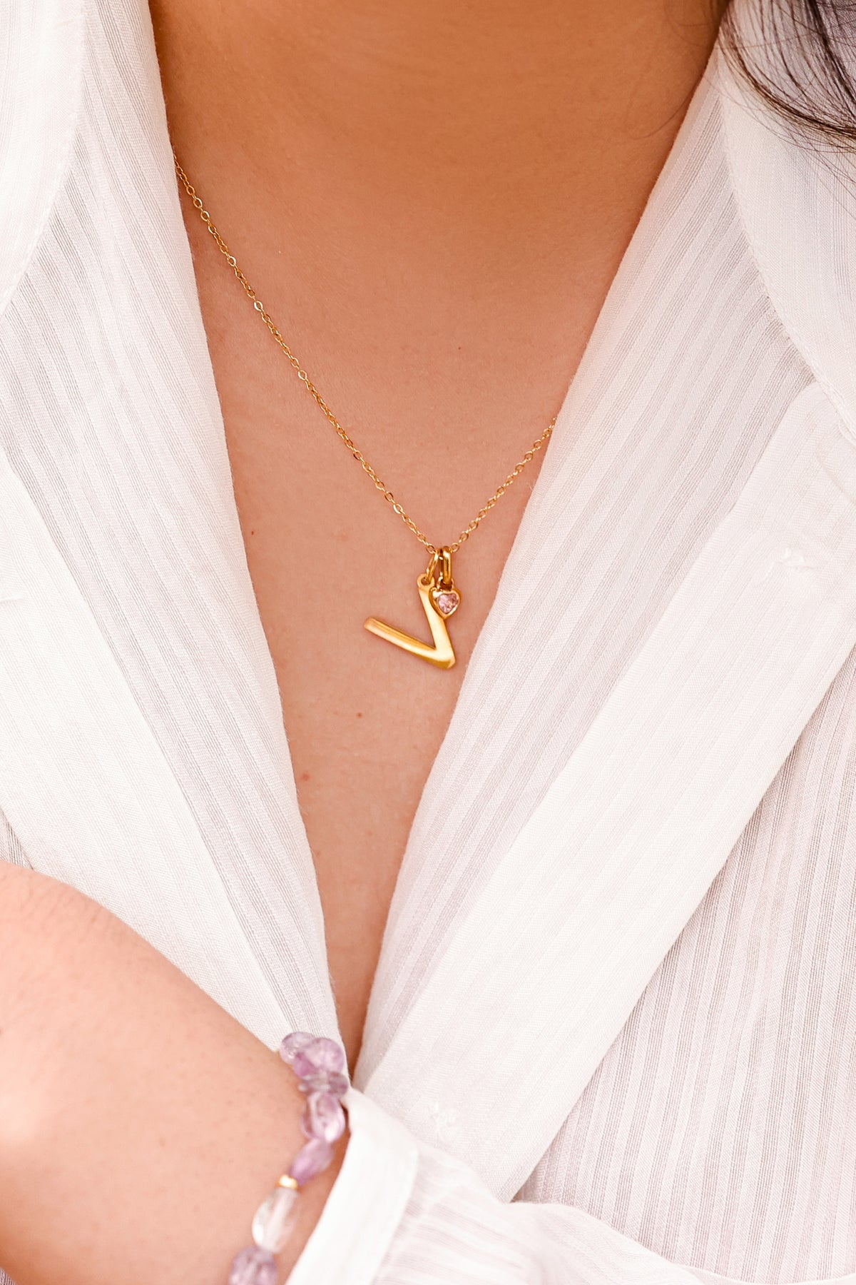 Initialen Kette mit Herz-Zirkonia – Frau trägt Kette mit Buchstabe V und rosa Herzstein, Nahaufnahme