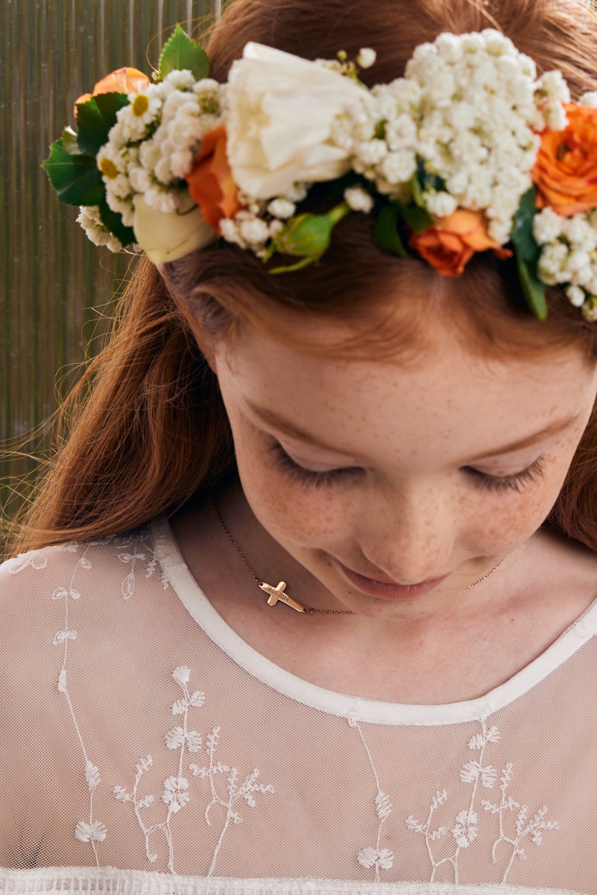 Kreuz Halskette mit Gravur – Mädchen mit Blumenkranz trägt roségoldene Kreuzkette, Nahaufnahme im Spitzenkleid