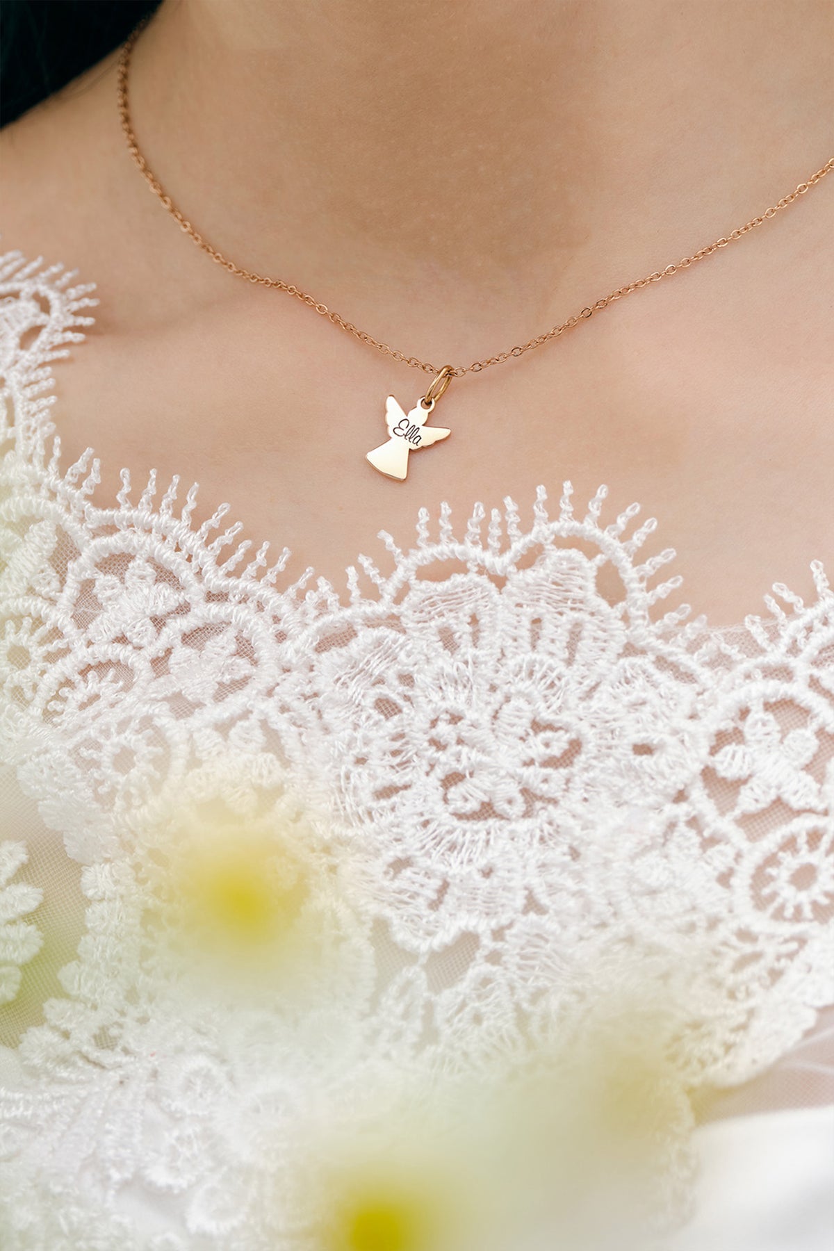 Schutzengel-Kette mit Gravur in Roségold getragen zu weißem Spitzenkleid, Nahaufnahme