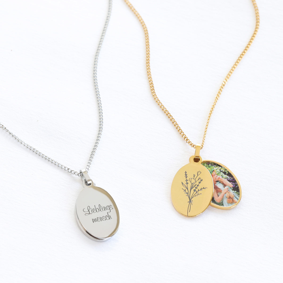 Foto-Medaillon mit Gravur in Silber mit Schriftzug 'Lieblingsmensch' neben goldener Variante mit Blumenmotiv und Foto