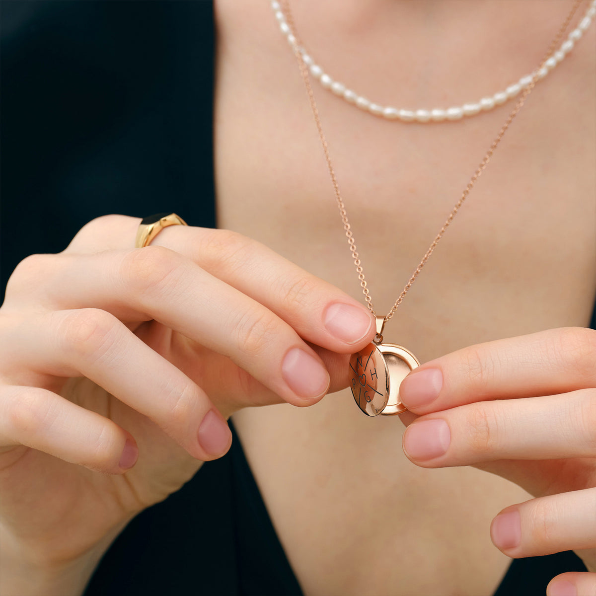 Geöffnete personalisierbare Medaillonkette mit Fotoeinsatz in Roségold, in Händen gehalten