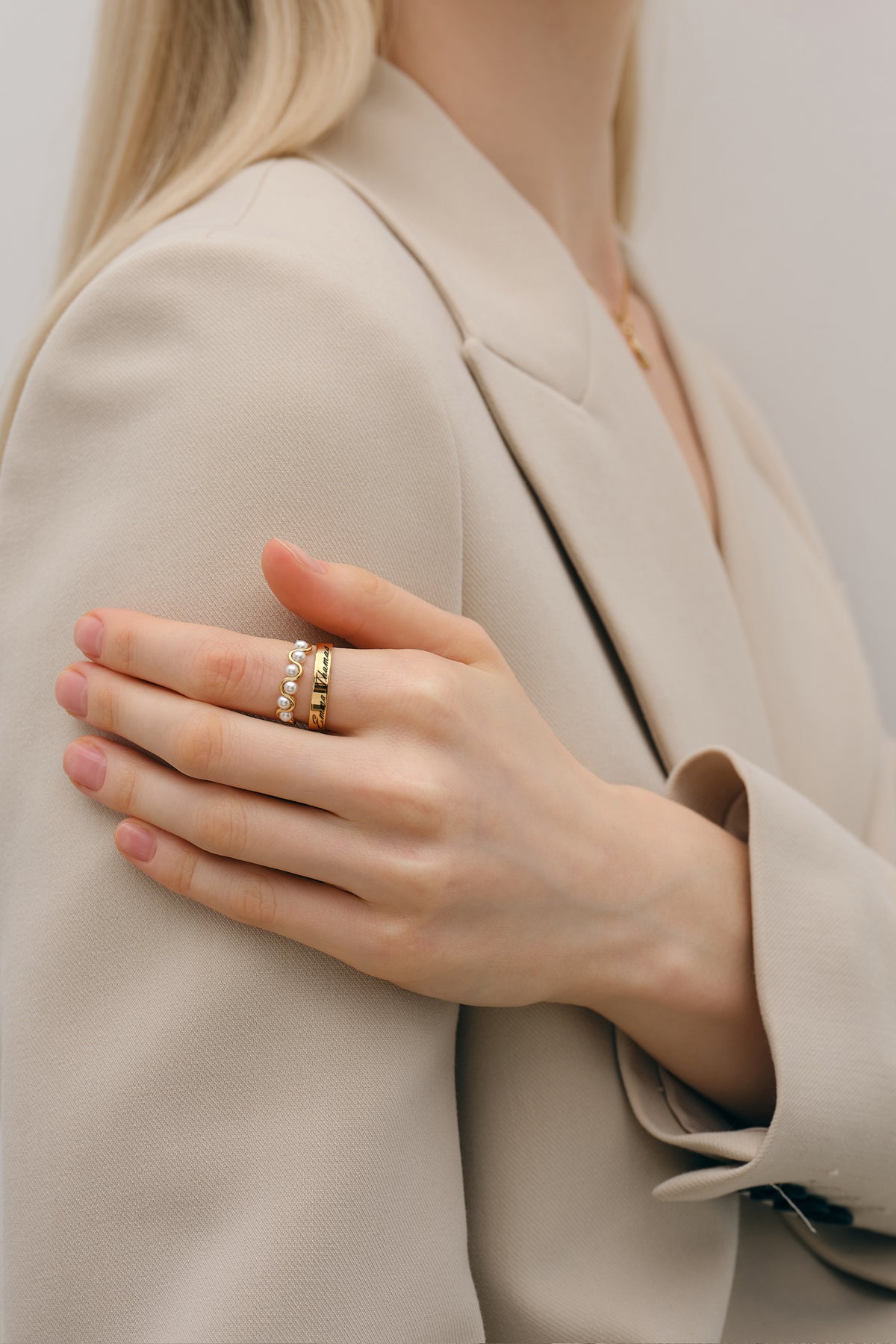 Frau im beigen Blazer trägt Minimalist Ring mit Gravur gestapelt mit Perlenring