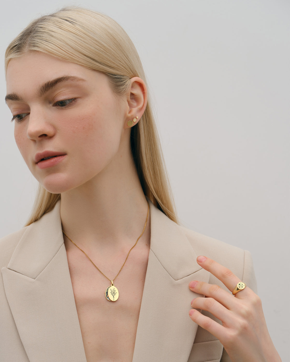Model im Blazer trägt Klassischer Siegelring mit Gravur - rund in Gold zu goldener Anhänger-Kette