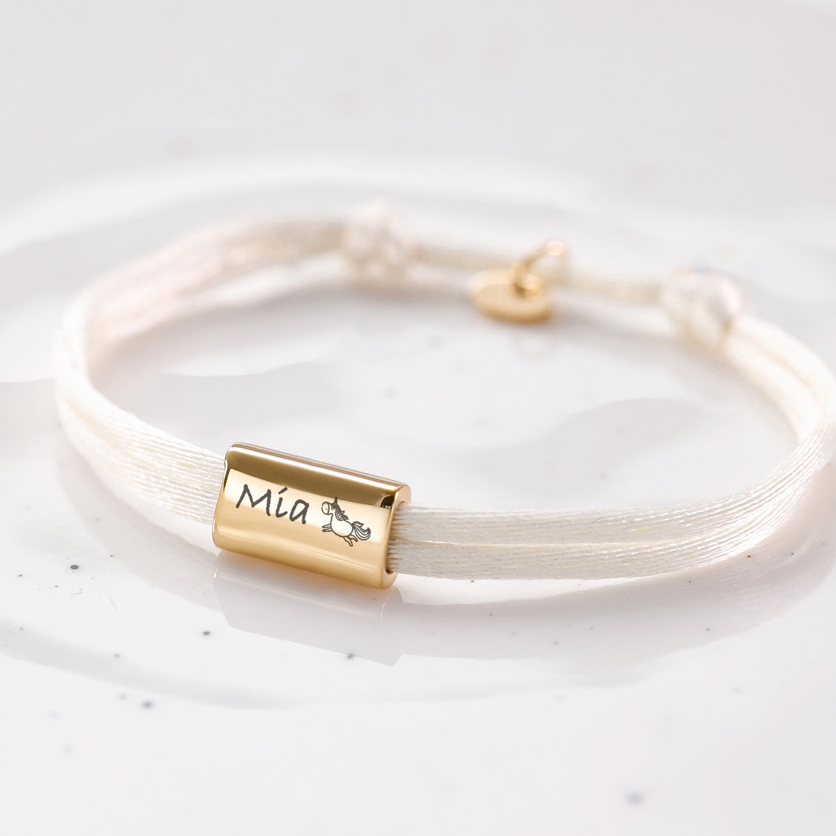 Kinder Satinband Armband mit Gravur in Creme, Gravur Mia mit Einhorn-Symbol und kleinem Anhänger
