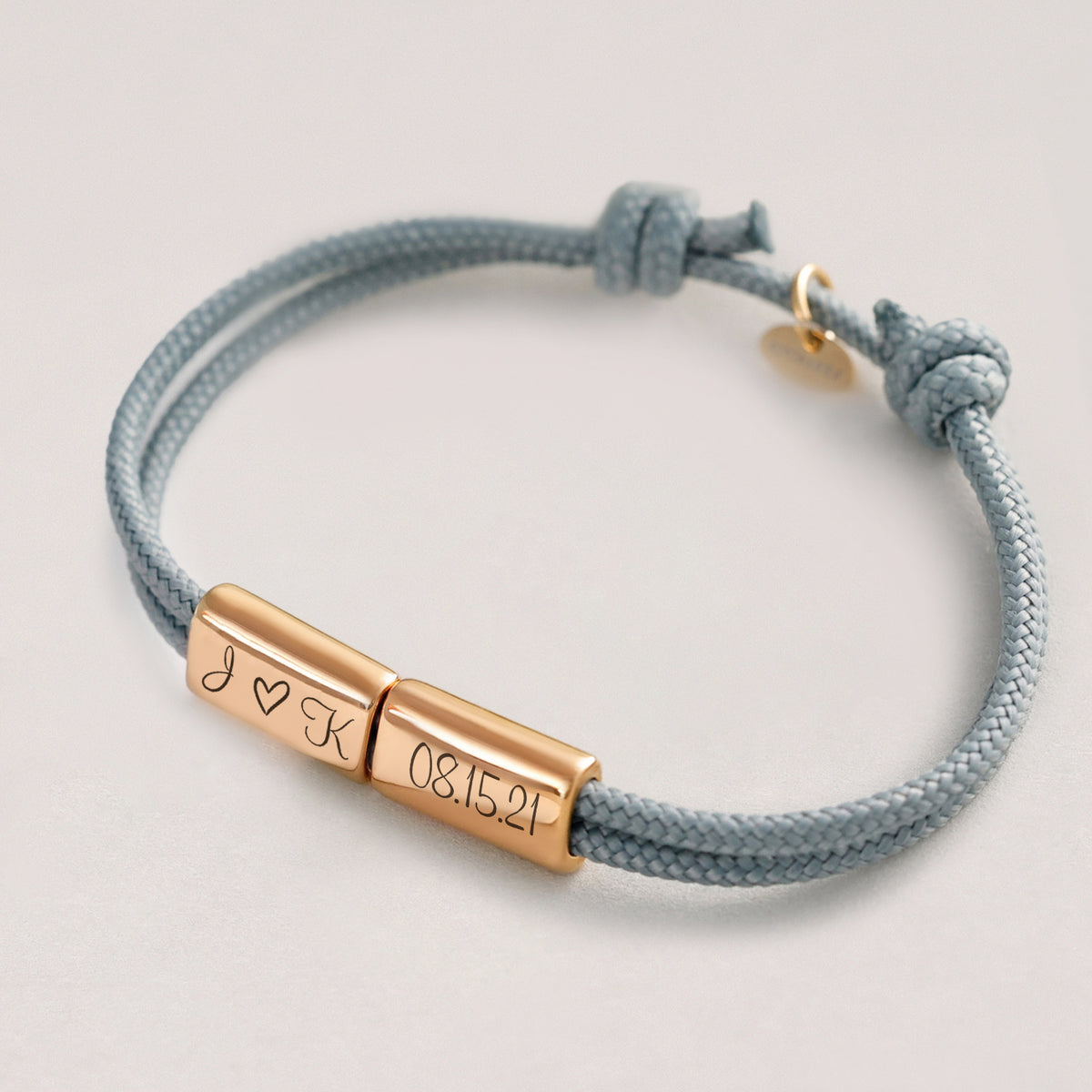 Segeltau Armband mit 2 Gravurperlen in Roségold – hellblaue Kordel mit Initialen 'J ♡ K' und Datum