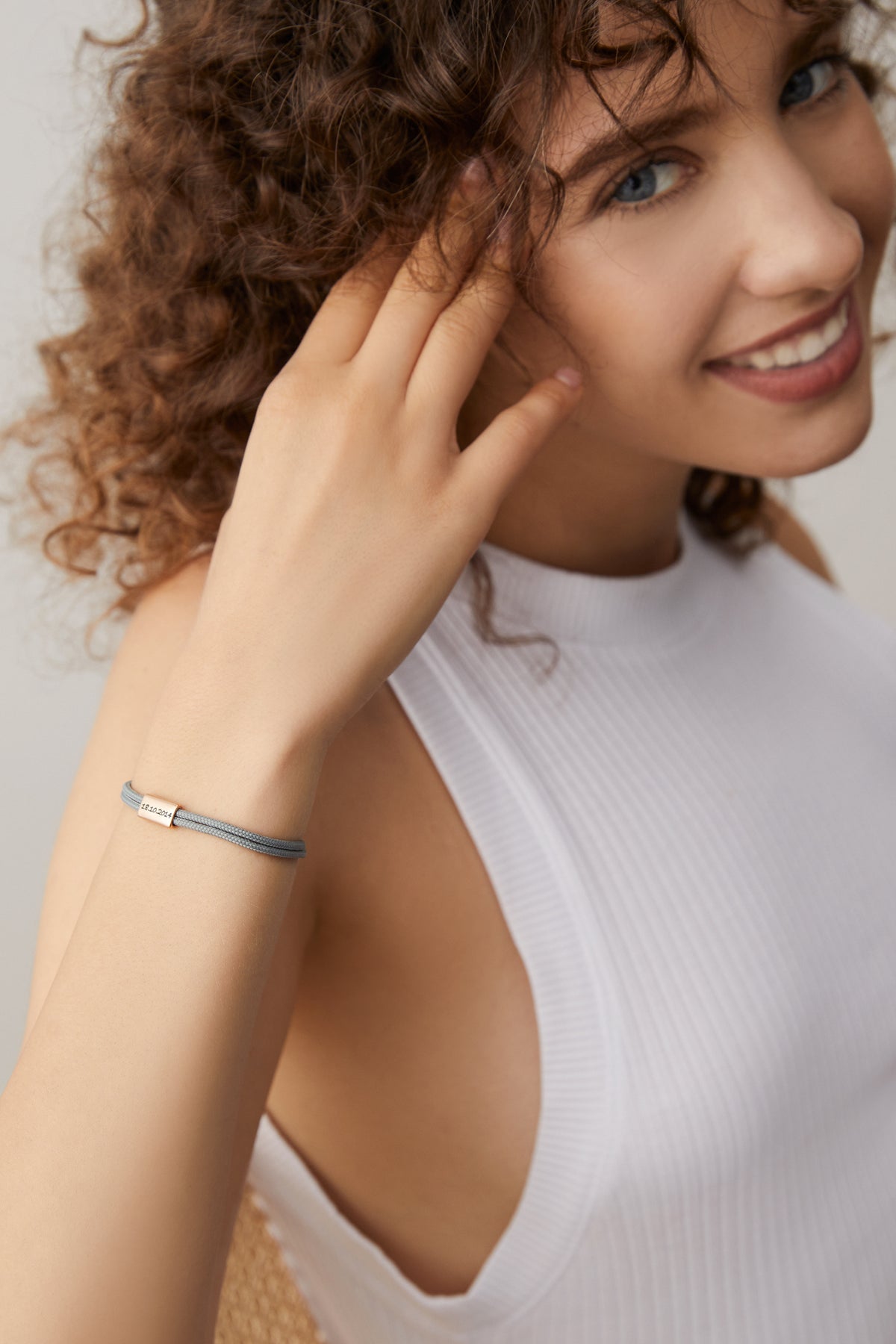 Frau trägt zartes Segeltau-Armband mit personalisierter Gravurperle in Graublau am Handgelenk