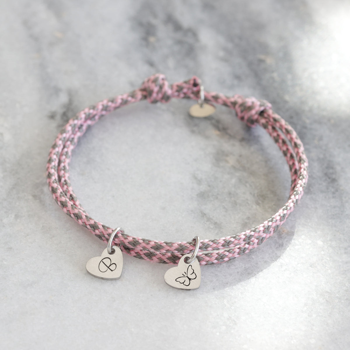 Herz-Armband aus Segeltau in Rosa-Grau meliert mit zwei Herzanhängern – Initiale und Schmetterling