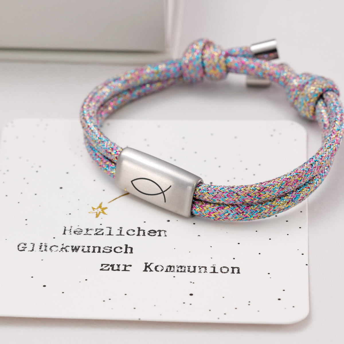 Glitzer Segeltau Armband bunt mit silbernem Plättchen und Fischsymbol neben Kommunions-Grußkarte