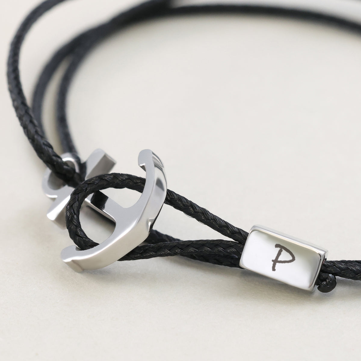 Nahaufnahme des schwarzen Unisex Armbands mit Ankerhaken & Gravur – silberner Anker mit Initiale P