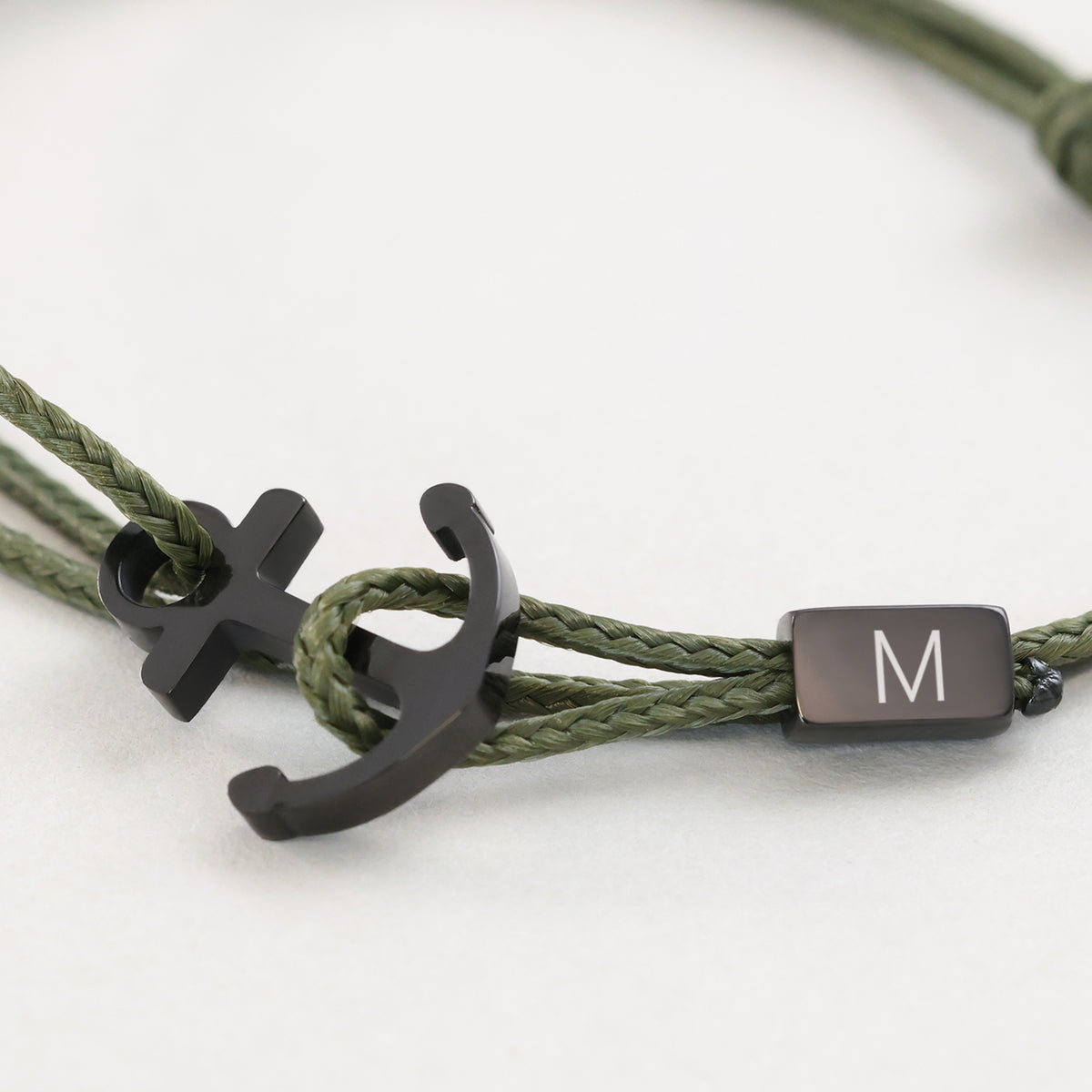 Nahaufnahme des Ankerhaken Nylon Armbands mit Gravur in Olivgrün – schwarzer Anker mit Initiale M