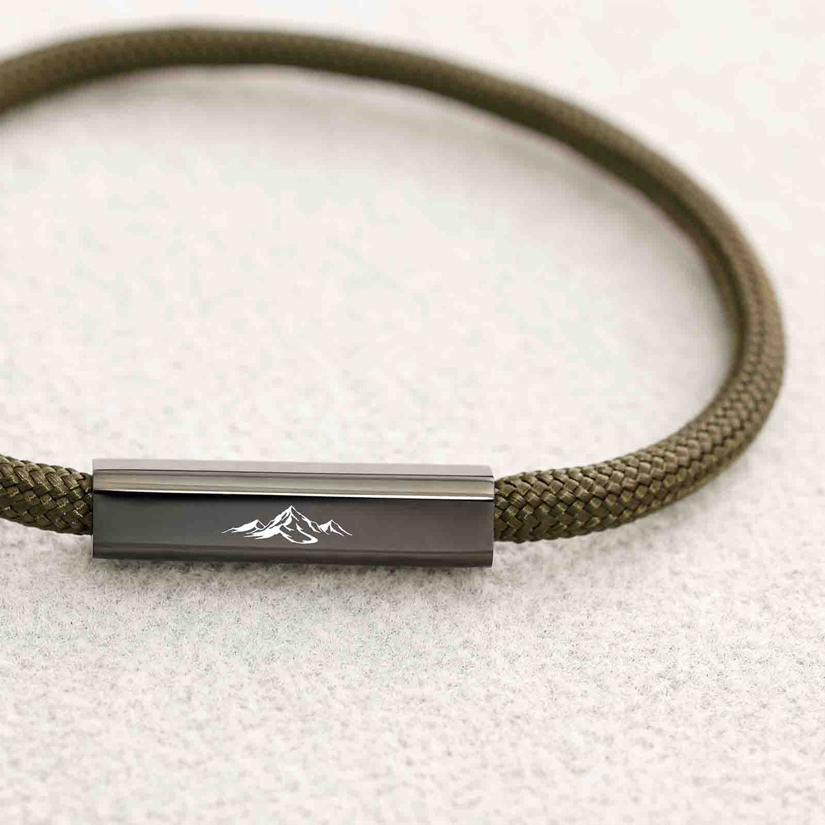 Detailaufnahme des Gravurplättchens mit Bergmotiv am olivgrünen Armband