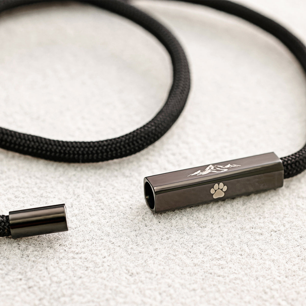 Personalisiertes Segeltau-Armband mit geöffnetem Magnetverschluss und Berg-Pfoten-Gravur