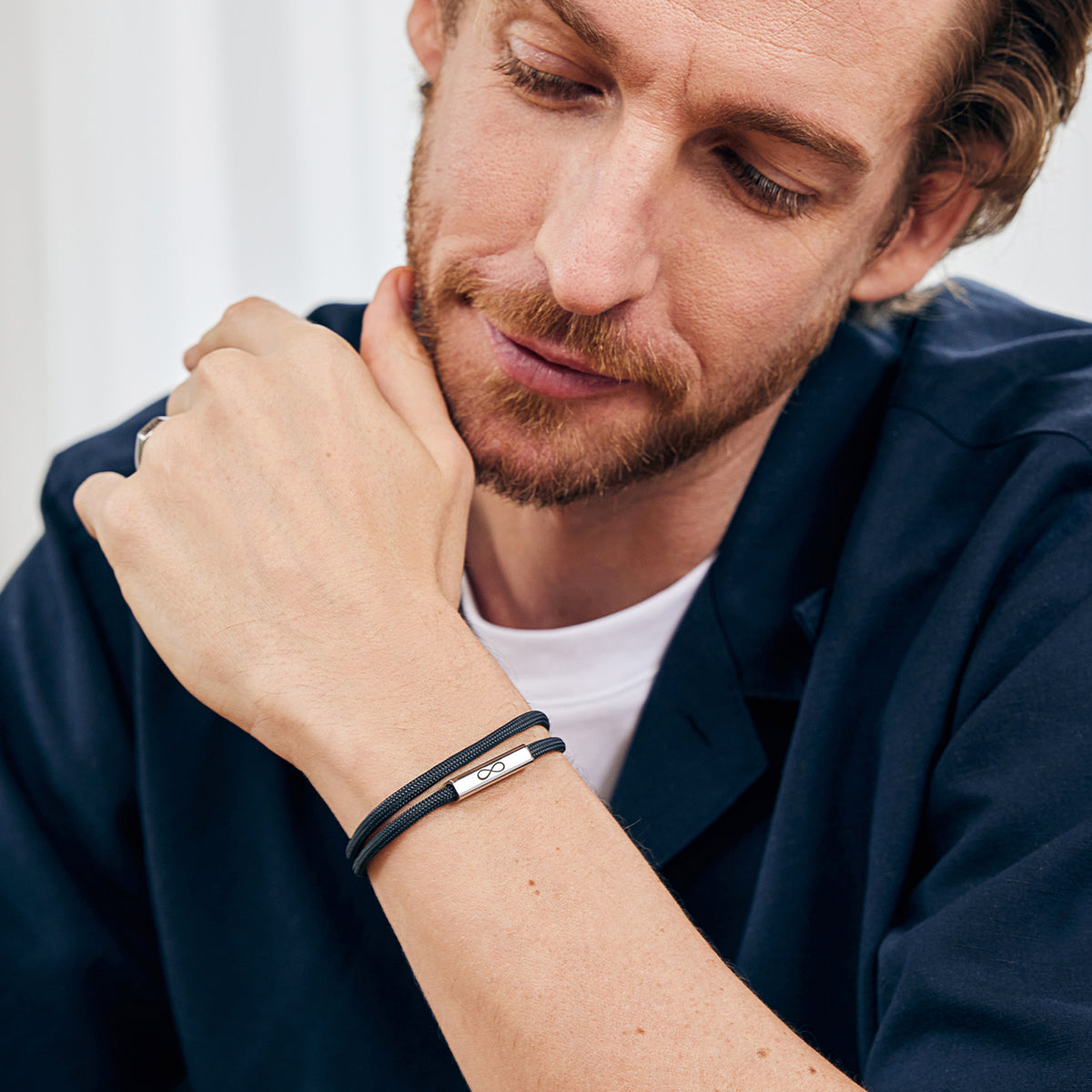 Mann trägt schwarzes Segeltau-Armband mit Gravur eines Unendlichkeitszeichens am Handgelenk