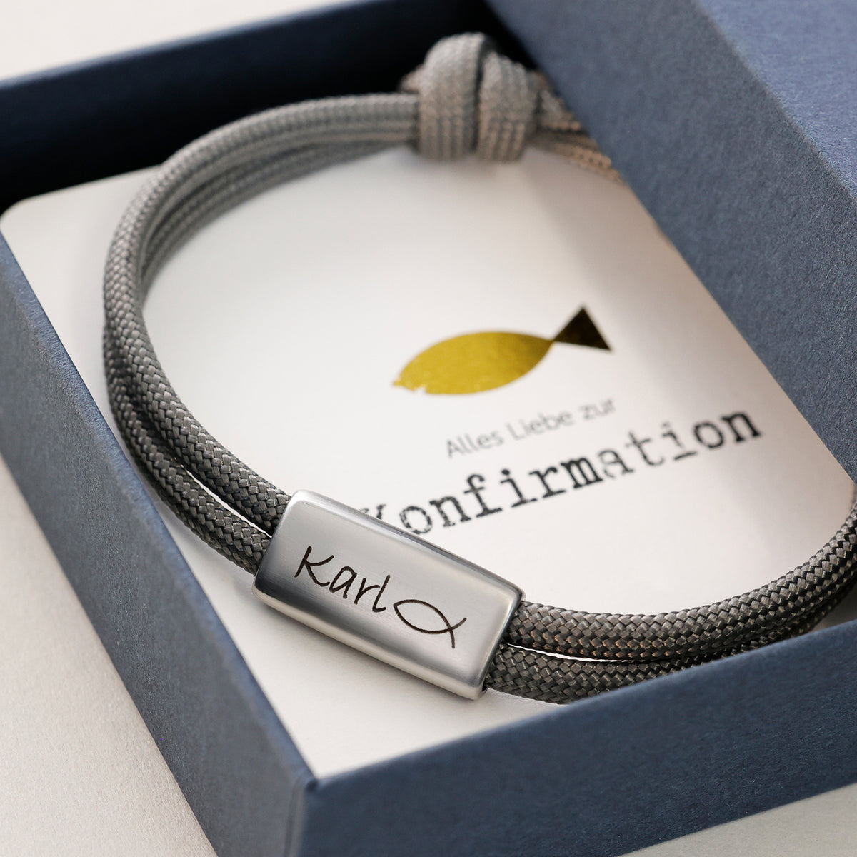 Personalisiertes Segeltau Armband mit Gravur zur Konfirmation – graues Band mit Name und Fischsymbol in Geschenkbox