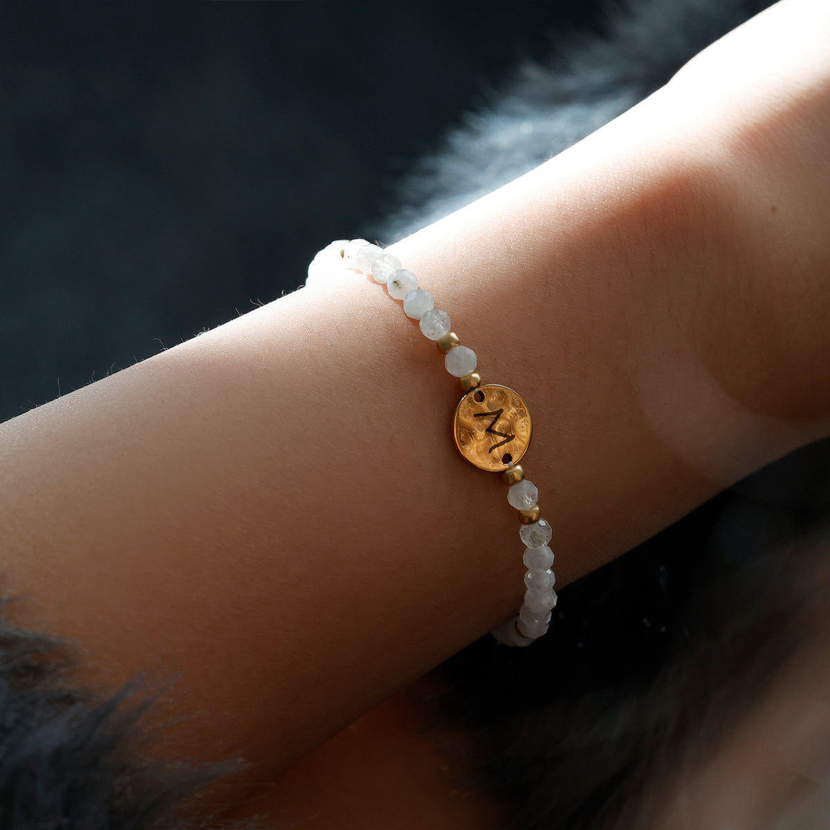 Frau trägt Mondstein Armband mit Hammerschlag Plättchen in Gold am Handgelenk