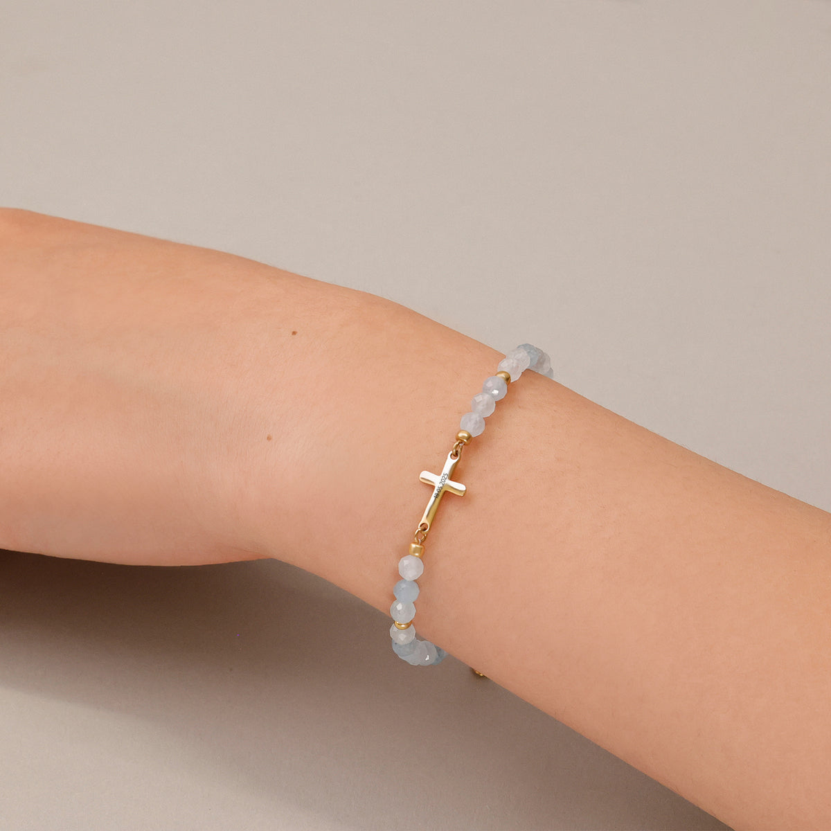 Frau trägt Aquamarin Kreuz Armband zur Kommunion am Handgelenk