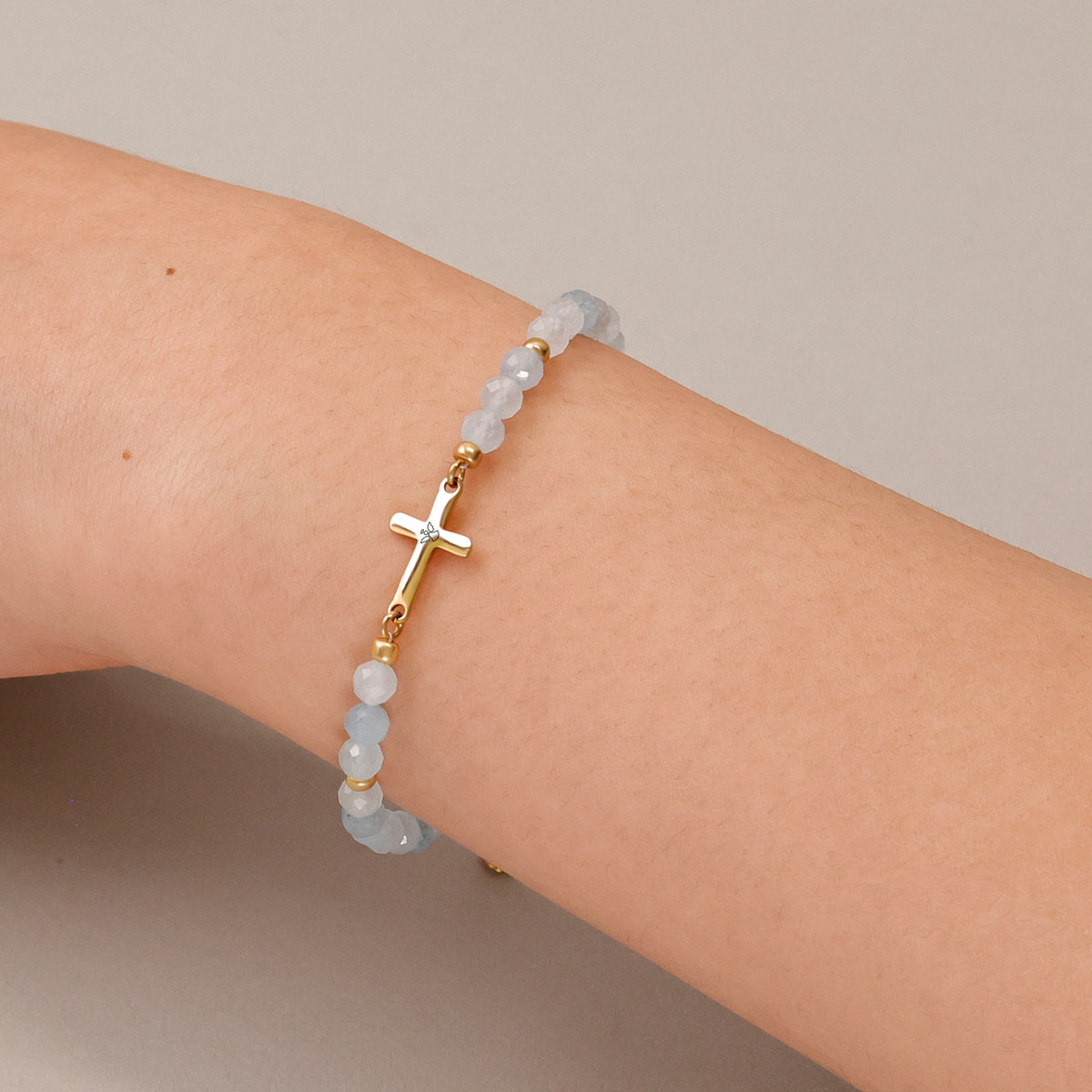 Frau trägt Aquamarin Kreuz Armband zur Konfirmation am Handgelenk
