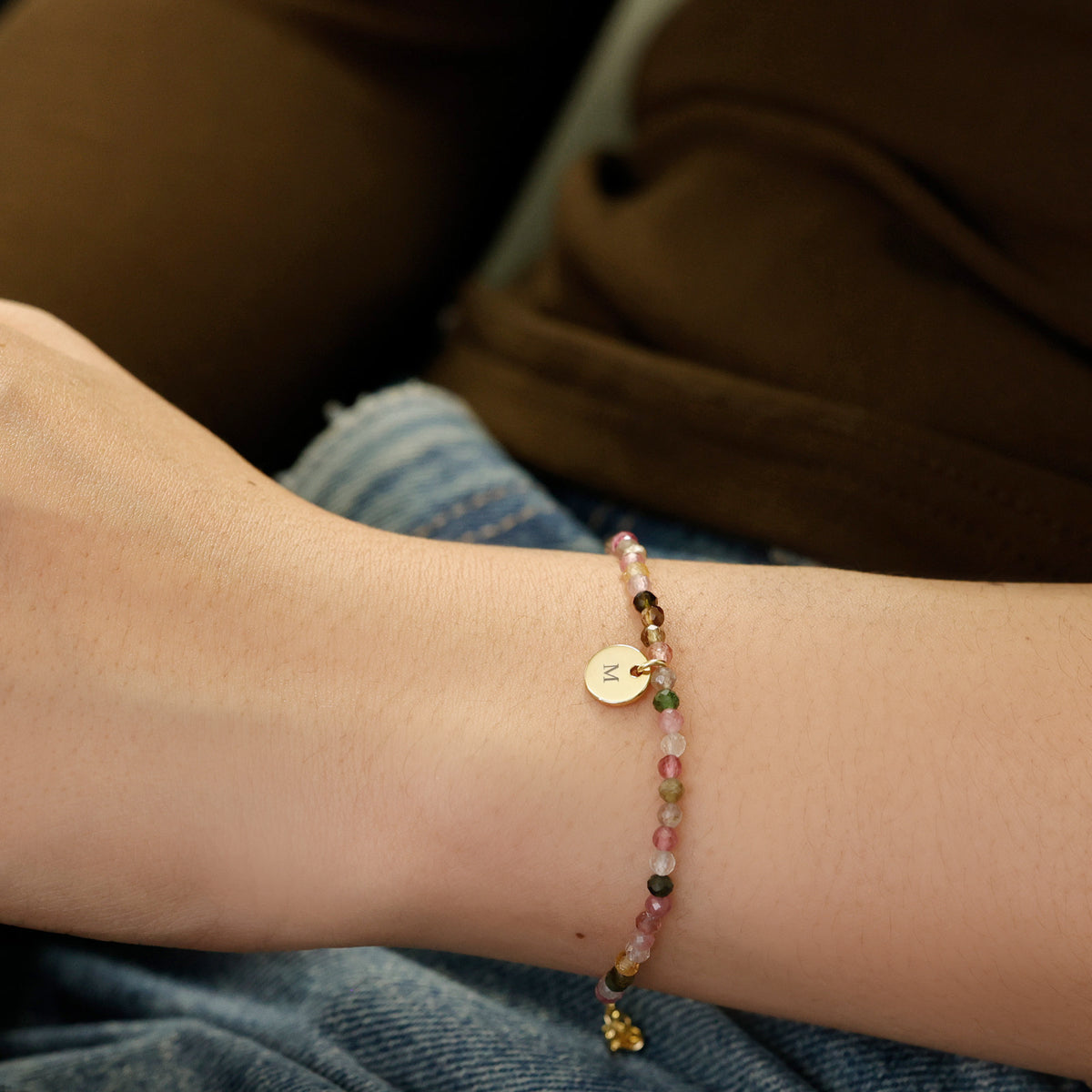 Regenbogen-Turmalin Armband am Arm getragen, Nahaufnahme des gravierten Plättchens
