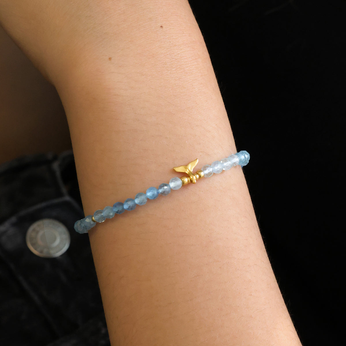 Frau trägt Aquamarin Armband mit Walflosse-Anhänger, Nahaufnahme am Handgelenk