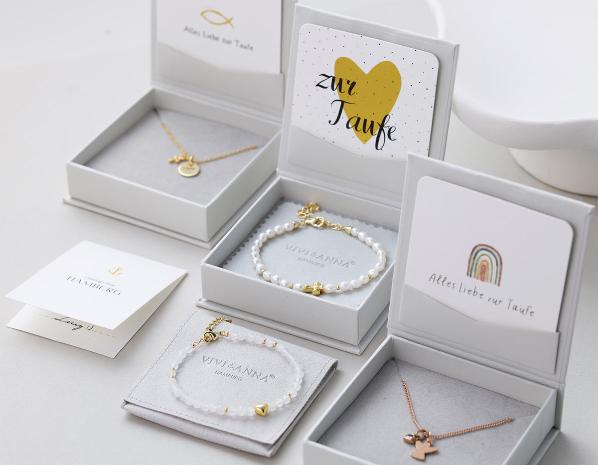 Mehrere Taufgeschenke in Boxen mit Perlenarmbändern, Kreuzkette und Karten 'zur Taufe'