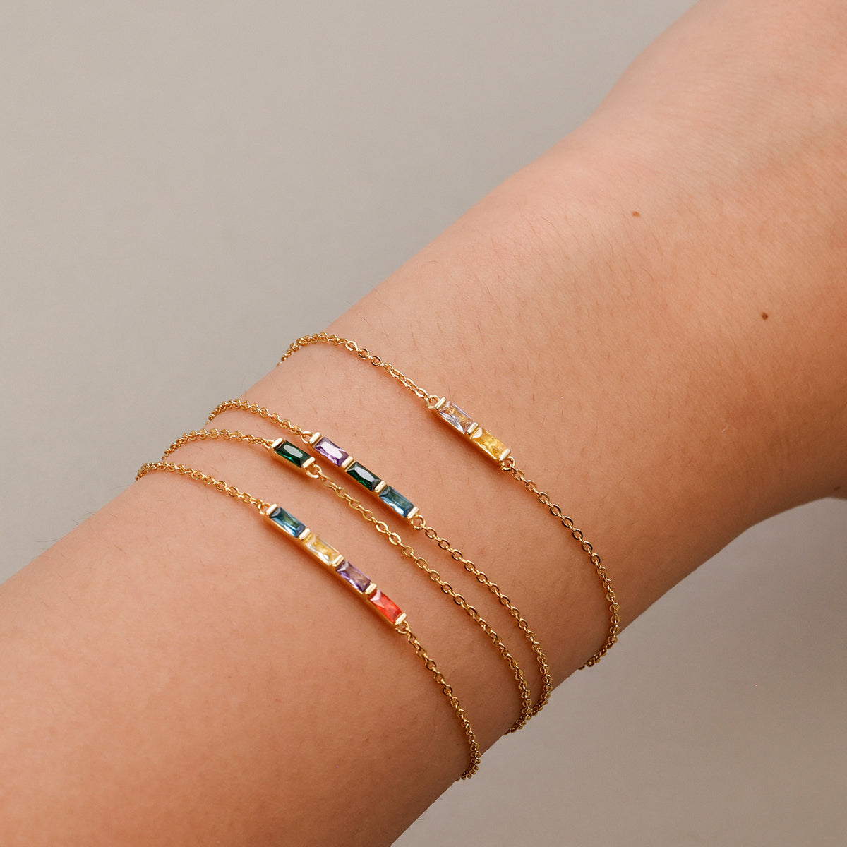 Personalisierte Geburtsstein-Armbänder in Gold mit bunten Steinen am Handgelenk im Detail