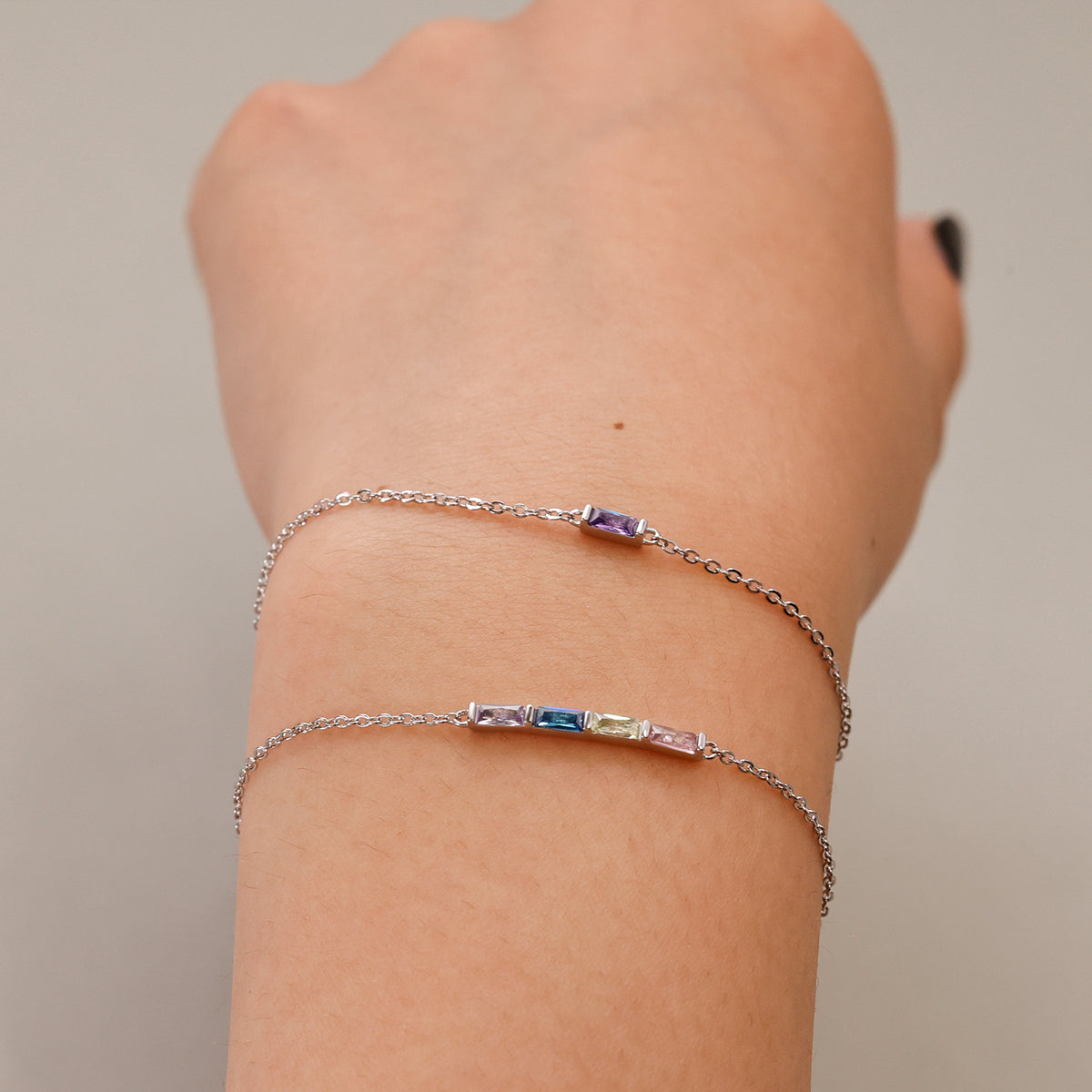Zwei personalisierte Geburtsstein-Armbänder in Silber am Handgelenk, ein- und mehrfarbig