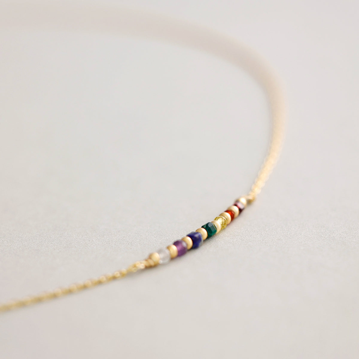 Chakra-Heilsteinkette in Gold, Makroaufnahme der bunten Chakra-Perlen