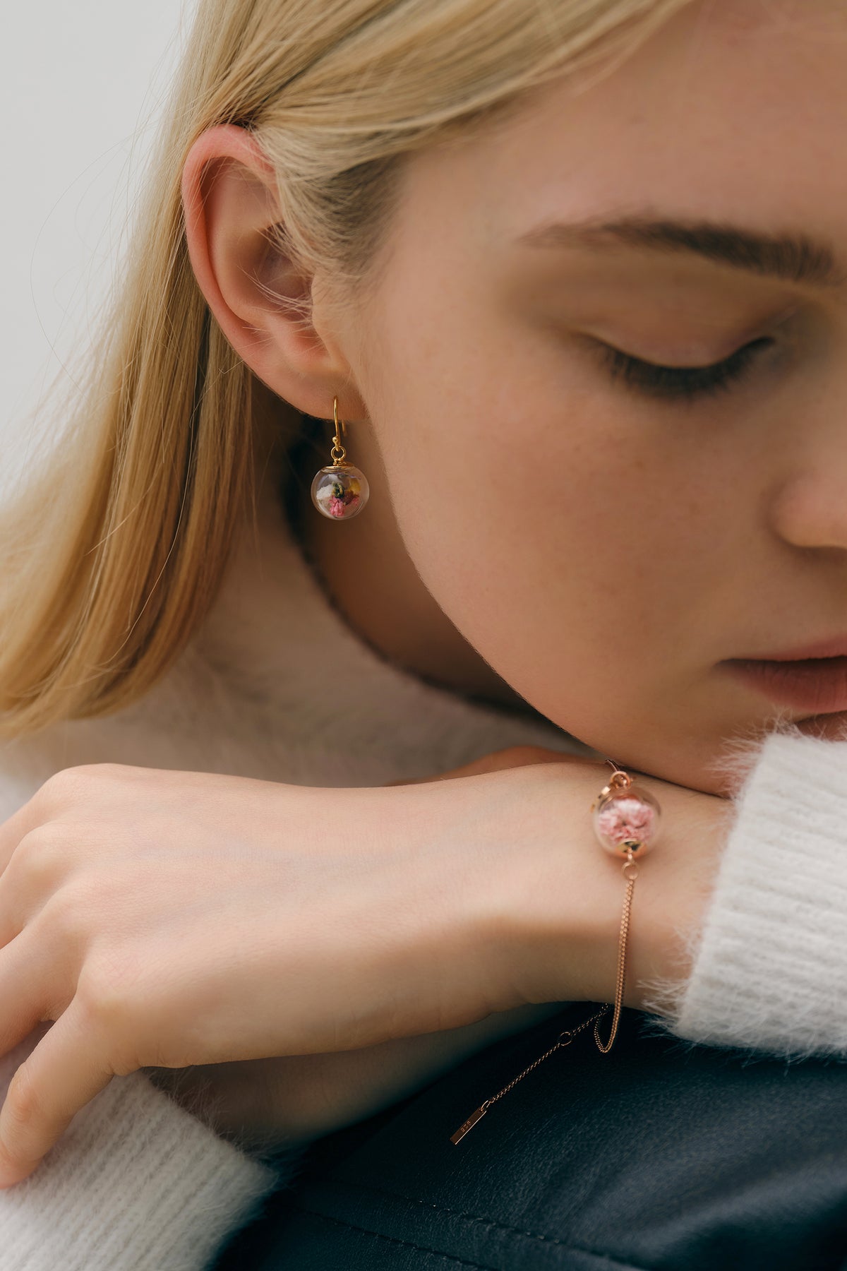 Frau trägt Echte-Blumen-Ohrring und Armband mit Blüten-Anhänger am Handgelenk