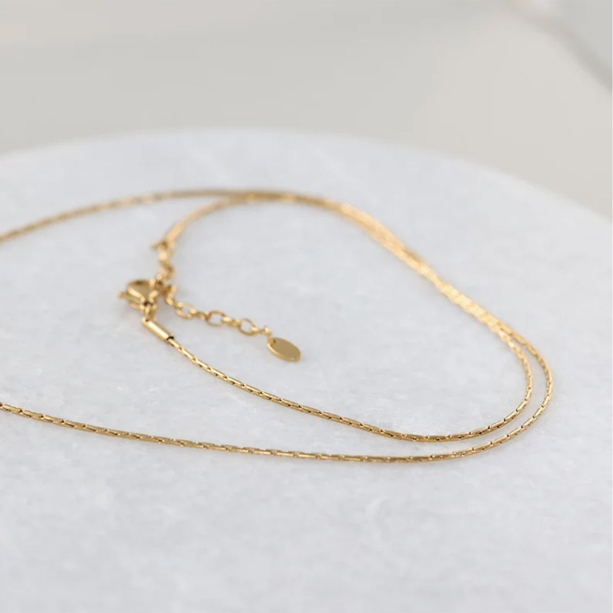 Palomakette - Herringbone Kette in Gold, doppelte Kettenstränge auf Marmoruntergrund