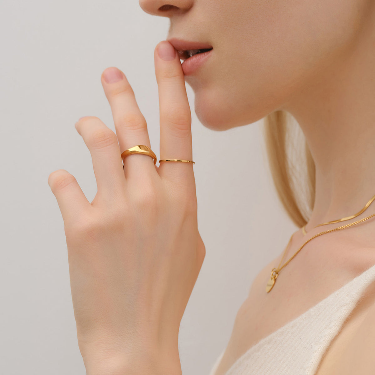 Feiner Stapelring in Gold – Frau trägt Ring kombiniert mit gewelltem Bandring am Finger