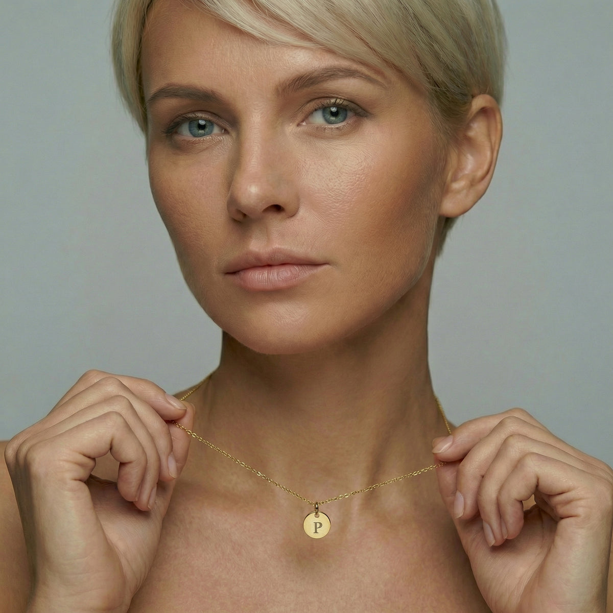 Model trägt personalisierte Goldkette mit graviertem Buchstaben-Plättchen am Hals