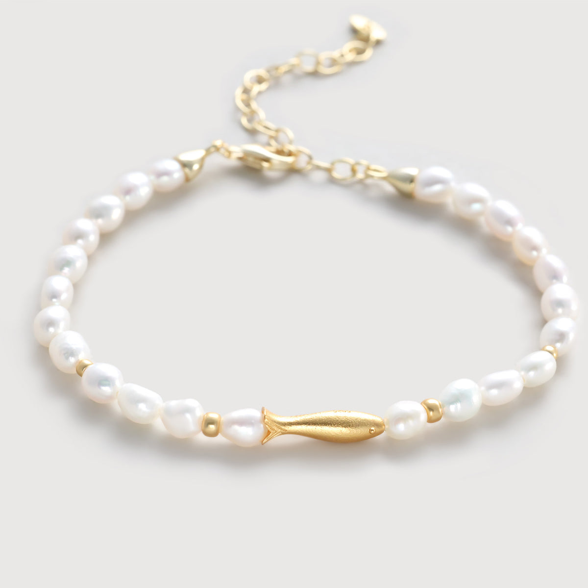 Zartes Fisch Armband aus Süßwasserperlen mit goldenem Fischanhänger – Flatlay der kompletten Perlenkette