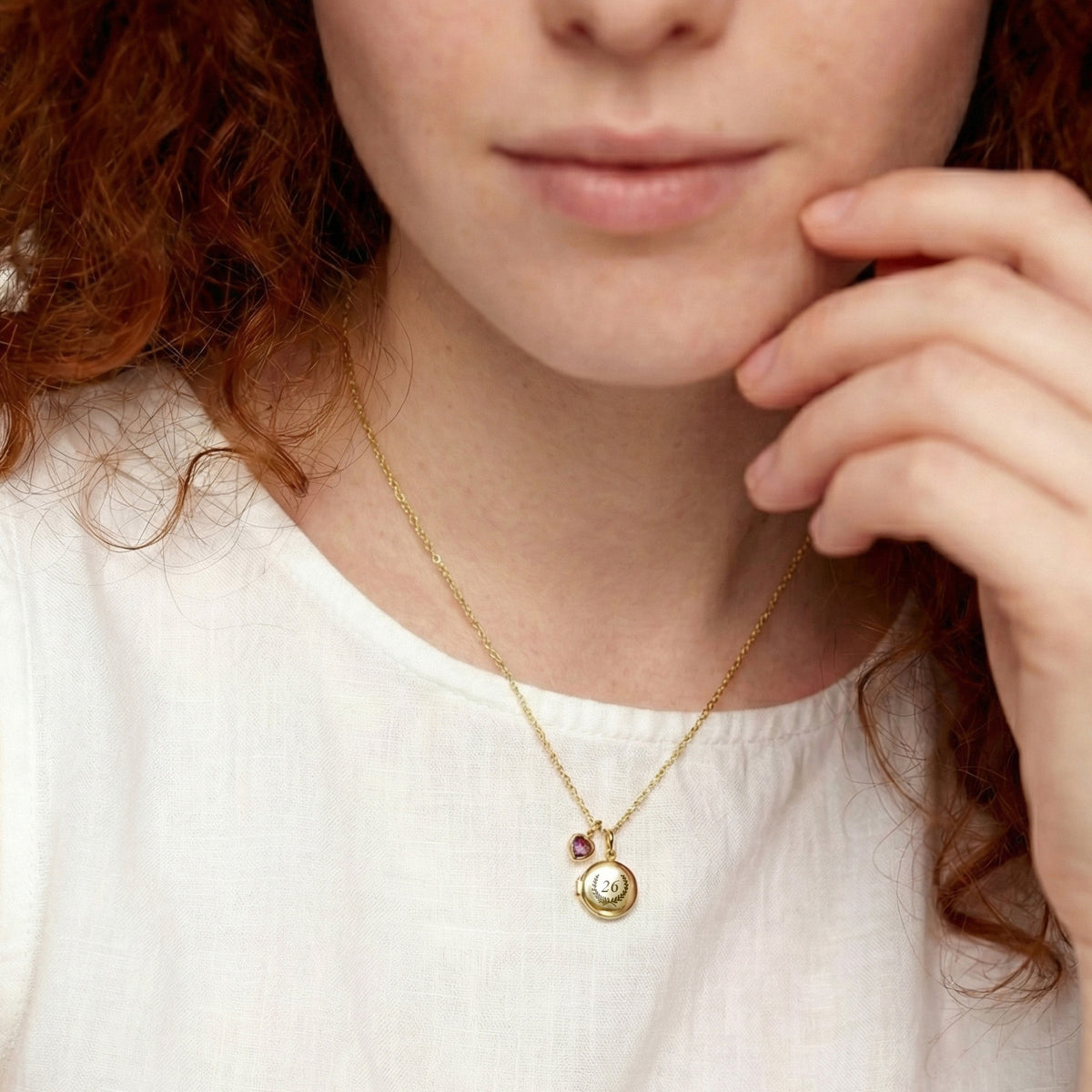 Frau trägt Mini Medaillon Kette mit Herz-Geburtsstein in Gold um den Hals