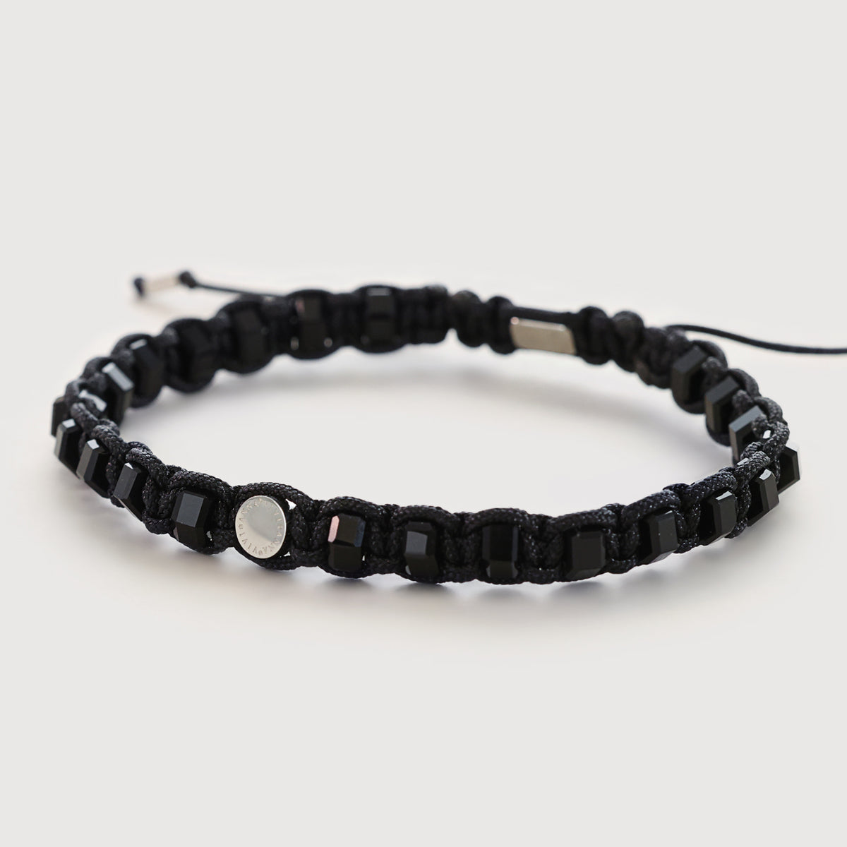 Makramee Armband mit schwarzem Onyx und runder Gravurplakette, flach liegend fotografiert