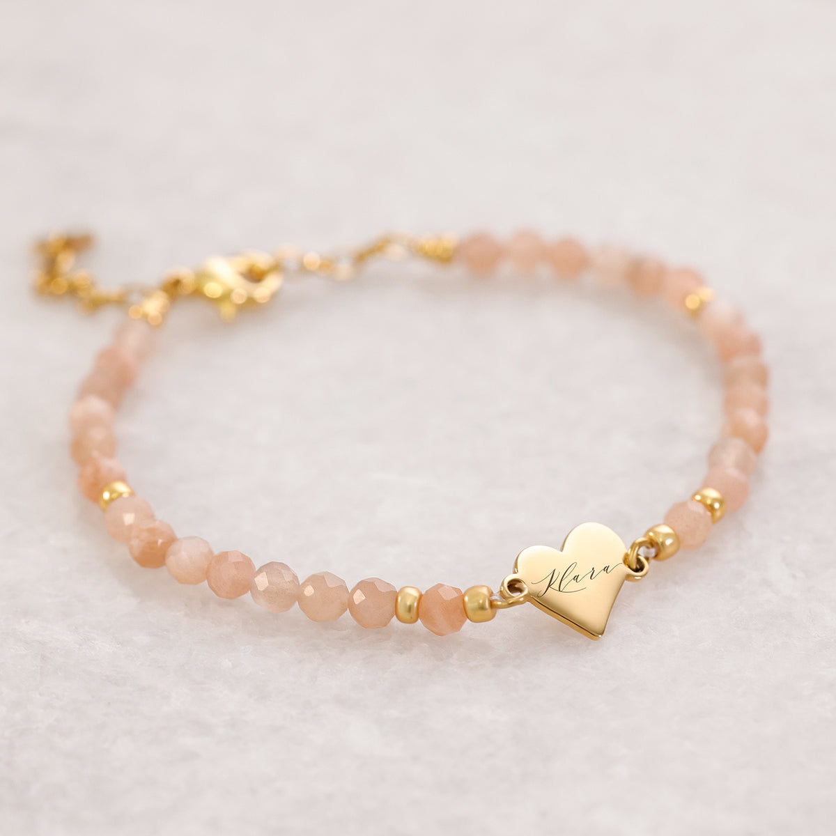Armband aus rosafarbenen Steinperlen mit goldenem Herzanhänger und Gravur 'Mara'