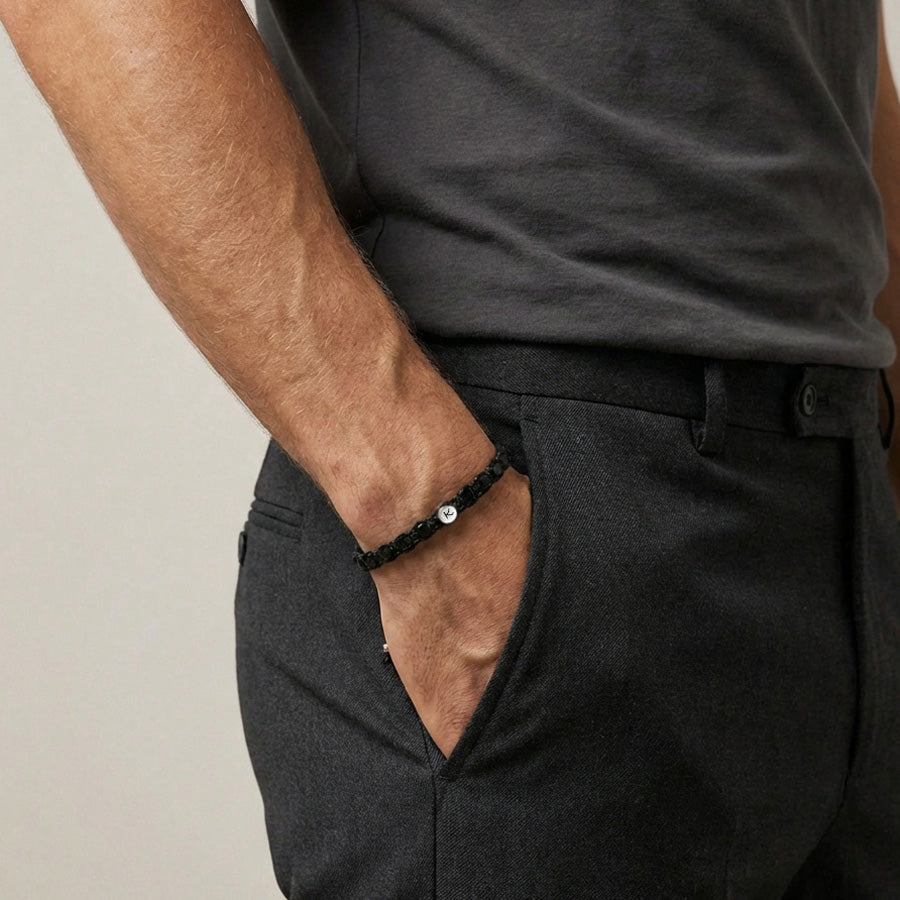 Mann trägt schwarzes Onyx Makramee Armband mit Silberplakette am Handgelenk, Hand in der Hosentasche