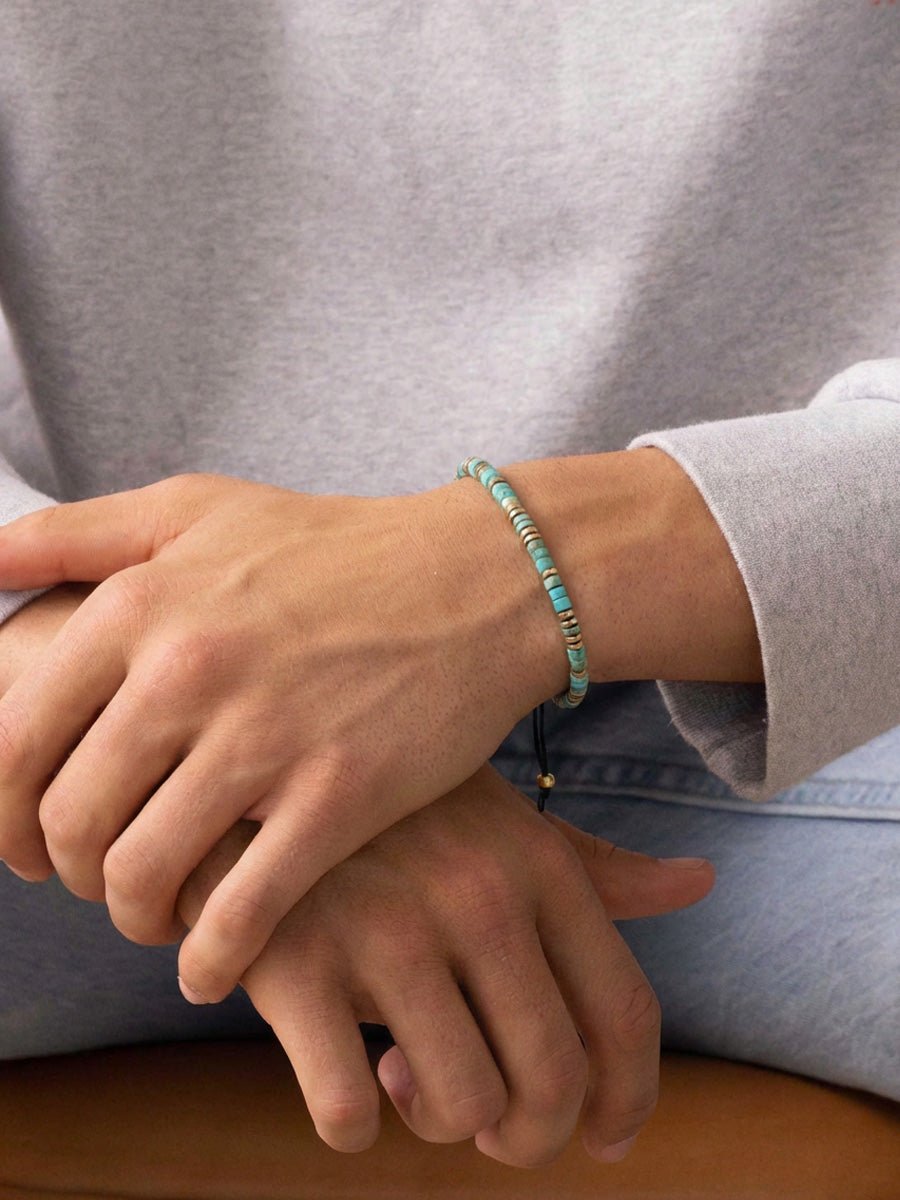 Person trägt Edelsteinarmband mit Türkis und Hämatit am Handgelenk, verstellbarer Zugverschluss sichtbar