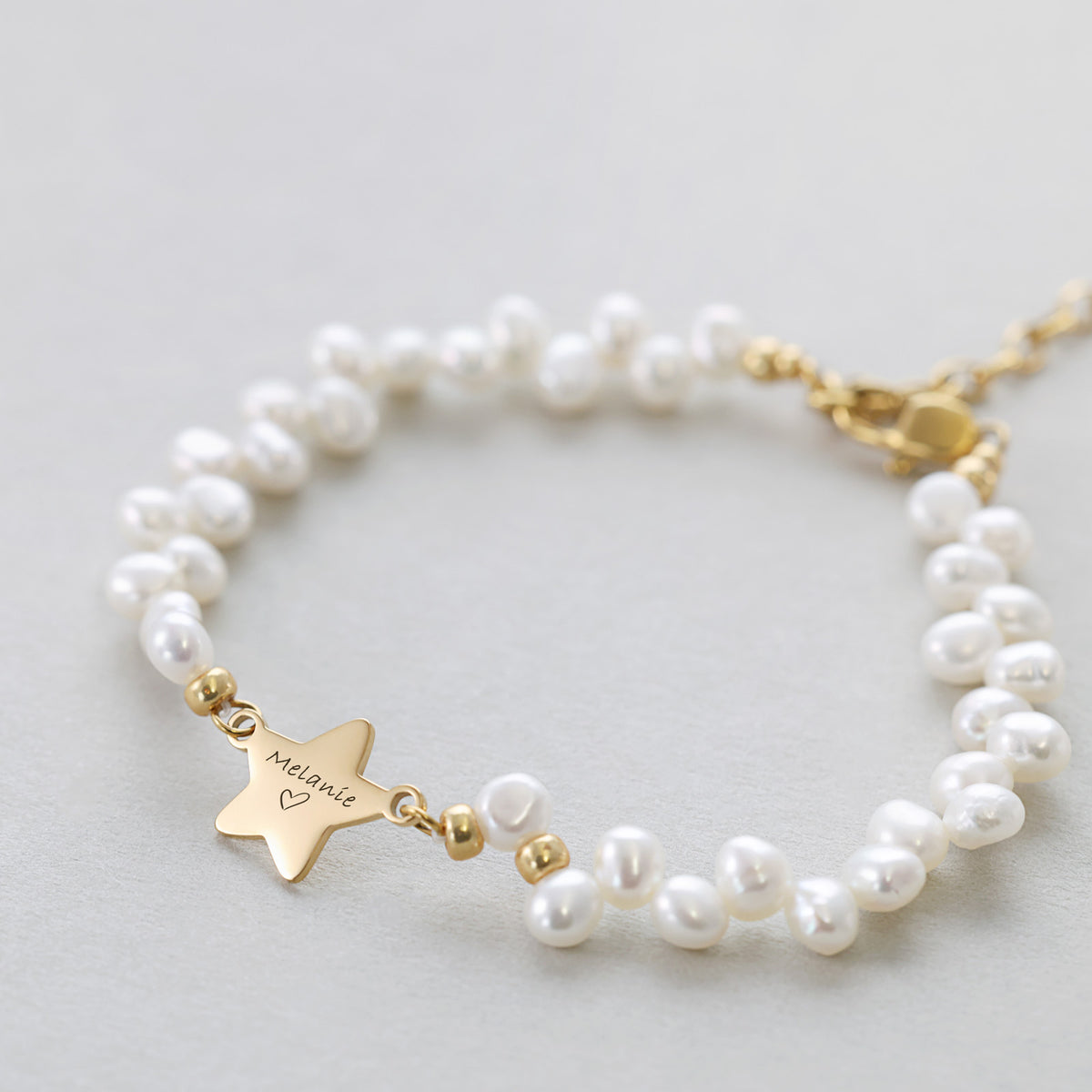 Süßwasserperlen Armband mit Sternanhänger 'Melanie' in Gold, ausgebreitet auf hellem Hintergrund