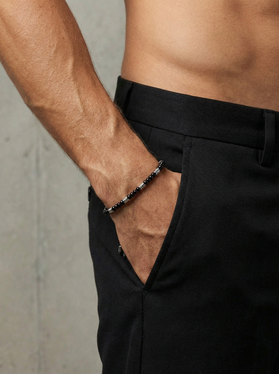 Mann trägt Edelsteinarmband mit schwarzem Onyx und Hämatit am Handgelenk, Hand in der Hosentasche
