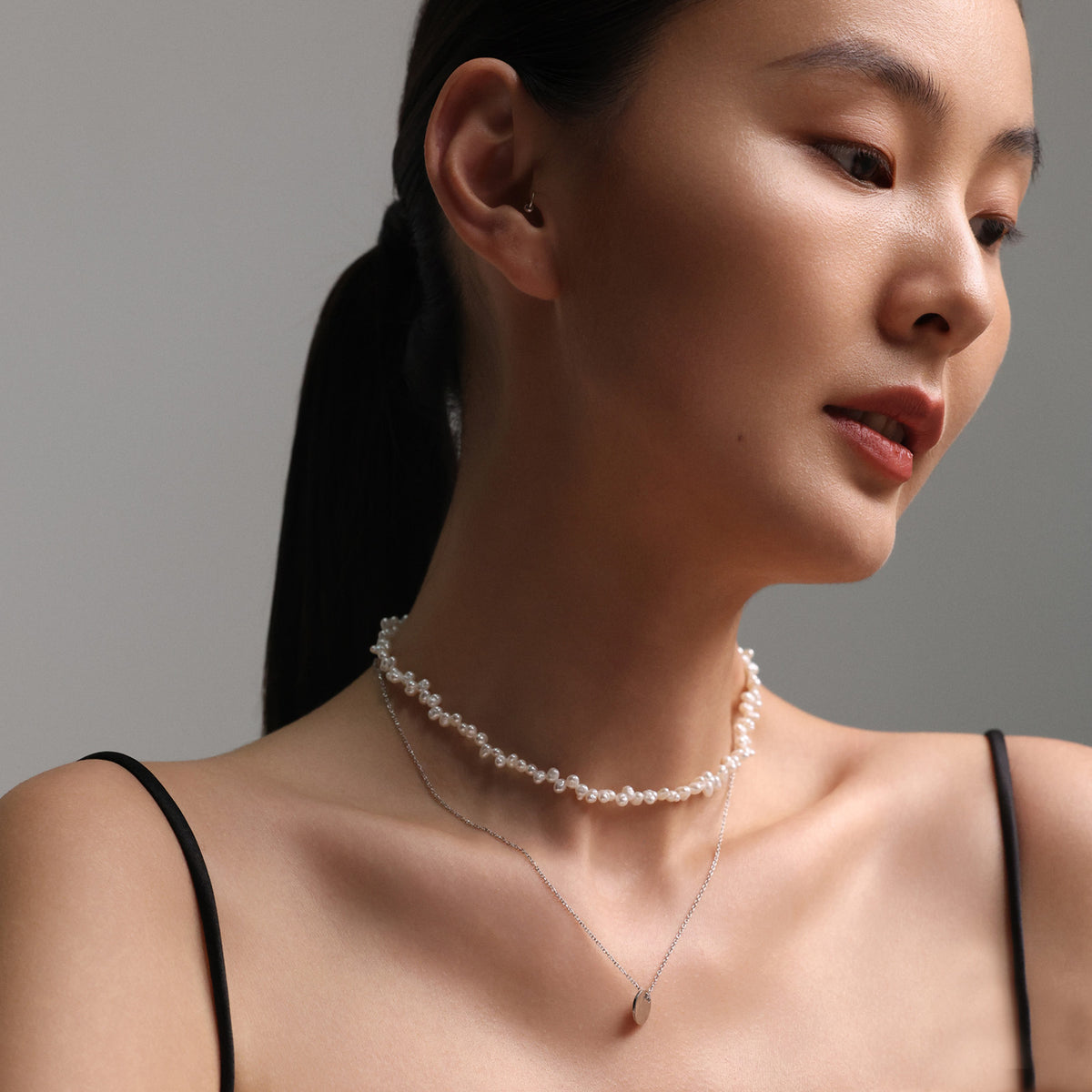 Frau trägt Süßwasserperlenkette in Spitzenoptik als Choker mit zweiter dünner Kette