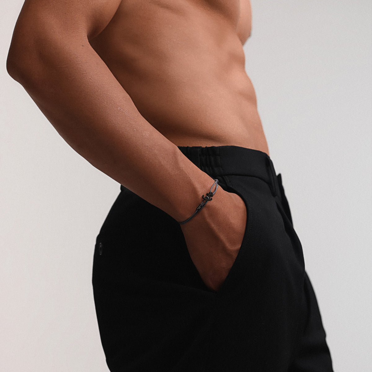 Mann trägt schwarzes Ankerhaken Nylon Armband mit Gravur am Handgelenk, nackter Oberkörper