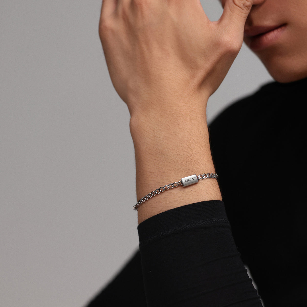 Mann trägt graviertes Cuban-Armband am Handgelenk, Datum auf dem Plättchen